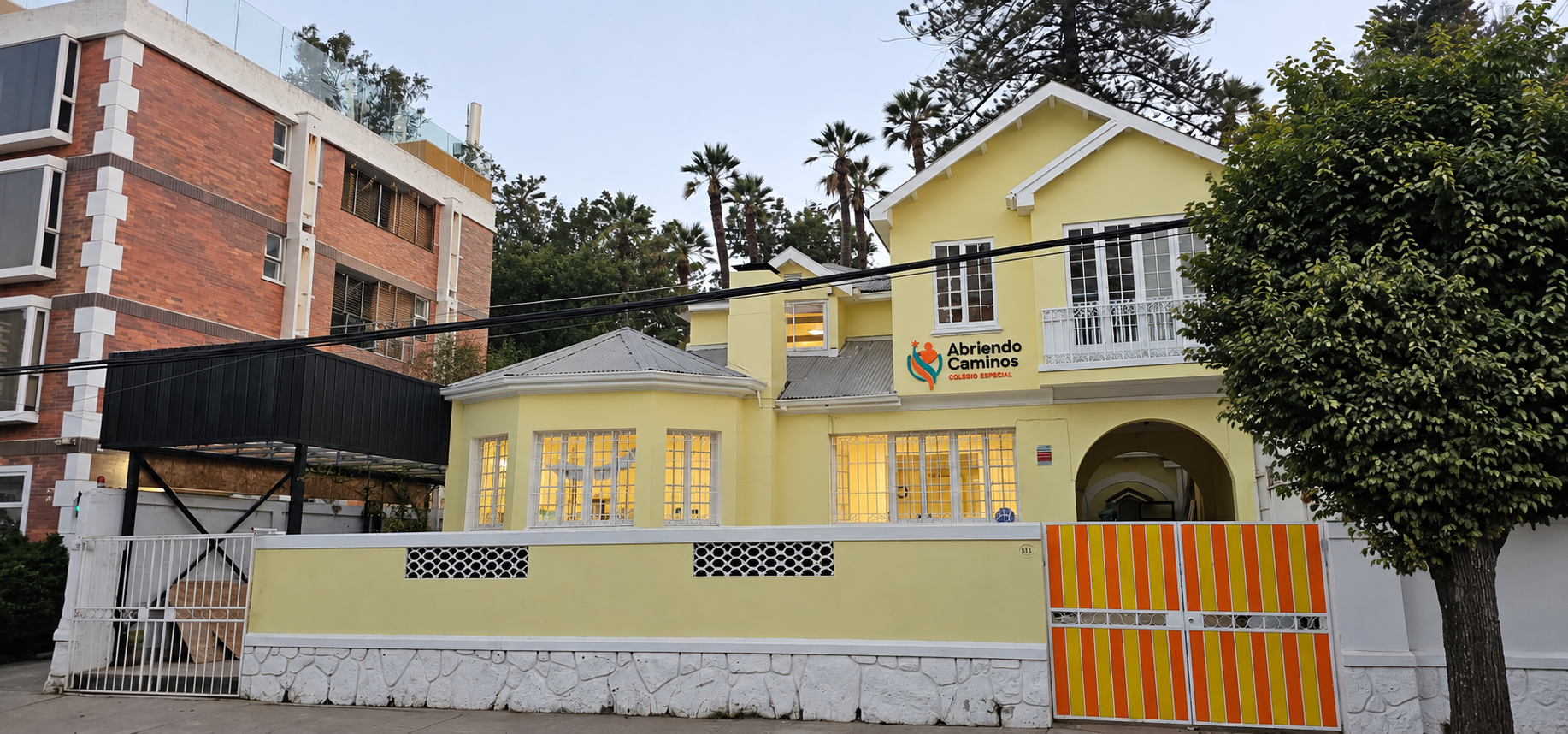 Fachada principal amarilla del Colegio Especial Abriendo Caminos, con el árbol ubicado al lado derecho